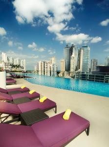 een rij paarse ligstoelen op het dak van een gebouw bij Megapolis Hotel Panama in Panama-Stad