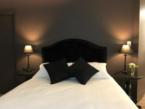 a white bed with two black pillows on it at Indulge at Daylesford in Daylesford
