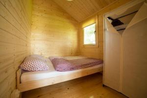 a small bed in a wooden cabin with a window at Morska Polana in Mielno