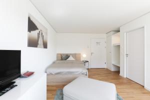 a white bedroom with a bed and a tv at Serviced Apartments Haus 1 in Uzwil