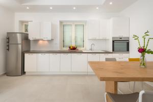 a kitchen with white cabinets and a wooden table at Urban Chic LUXE apartments near Beach Bačvice & CENTRE in Split