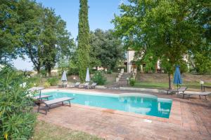 una piscina con bancos y sombrillas en un patio en Villa Gemelli, en Volterra