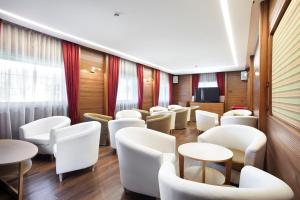 una sala de espera con sillas y mesas blancas en Hotel Haus Michaela, en Sappada