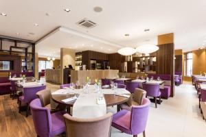 a dining room with tables and purple chairs at Hotel DeSilva Premium Poznań in Poznań