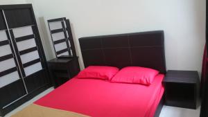 1 dormitorio con 1 cama con sábanas rosas y cabecero negro en Ila Homestay, en Senawang