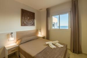 1 dormitorio con 1 cama con 2 toallas en Apartamentos Costa Luz Punta Umbría, en Punta Umbría