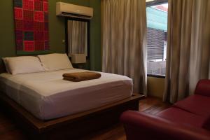 een slaapkamer met een bed, een raam en een bank bij Purple Tree Bed & Breakfast in Manilla