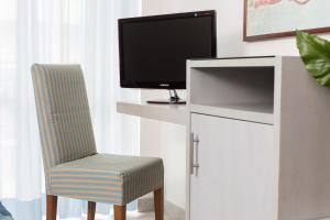 a living room with a tv and a chair at Hotel Imperiale in Milano Marittima