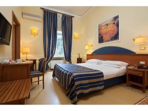 una camera d'albergo con letto, scrivania e TV di Hotel Kennedy a Roma