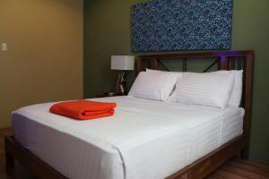 een bed met een oranje handdoek erop bij Purple Tree Bed & Breakfast in Manilla