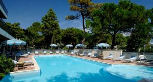 a swimming pool with lounge chairs and umbrellas at Hotel Imperiale in Milano Marittima