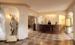 a woman standing at a counter in a lobby at Hotel Imperiale in Milano Marittima +19 photos