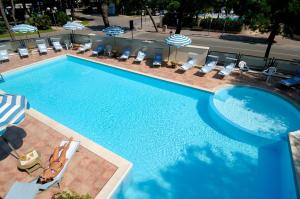 een groot zwembad met stoelen en parasols bij Hotel Imperiale in Milano Marittima