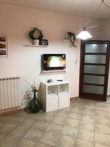 a living room with a tv and a white cabinet at Claves Claustri - Appartamento storico con balcone in Sarteano
