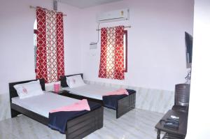 two beds in a room with red curtains at Hotel Nippon Palace in Tarangambādi