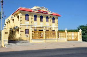 a yellow building with a fence in front of it at Hotel Nippon Palace in Tarangambādi