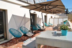 eine Terrasse mit blauen Stühlen, Tischen und Sonnenschirmen in der Unterkunft Vincci Lys in Valencia