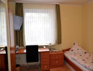 Schlafzimmer mit einem Bett, einem Schreibtisch und einem Fenster in der Unterkunft Hotel Waldersee in Hannover