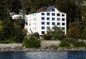 a large white building next to a body of water at Apart Costa Azul in San Carlos de Bariloche