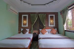 twee bedden in een kamer met twee ramen bij RS II Guesthouse in Phnom Penh