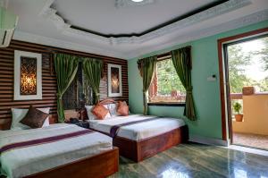 2 letti in una camera con pareti e finestre verdi di RS II Guesthouse a Phnom Penh
