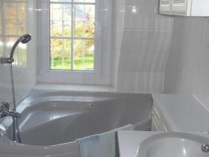 baño con bañera, lavabo y ventana en La peyrolyse, en Malvézie