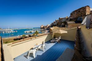 a balcony with chairs and an umbrella and the water at N'amuri Residence in Castellammare del Golfo