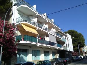 a white building with balconies and cars parked on the street at Apartament Passeig Maritim in Llança