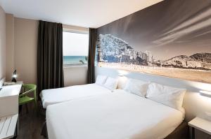 2 łóżka w pokoju hotelowym ze zdjęciem plaży w obiekcie B&B HOTEL Alicante w Alicante