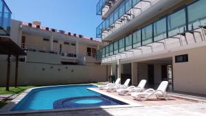 a swimming pool with lounge chairs next to a building at Manawa Beach Flats Prime in Porto De Galinhas