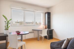 ein Wohnzimmer mit einem Tisch und weißen Stühlen in der Unterkunft City Résidence Lyon Marcy in Marcy-lʼÉtoile