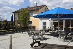 un groupe de tables et de chaises avec un parapluie bleu dans l'établissement Berghofstüble Obermarchtal, à Obermarchtal