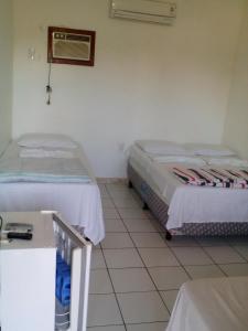 um quarto com duas camas e uma mesa em Pousada São Nunca em Ilha de Comandatuba