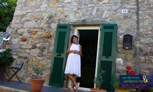 Eine Frau in einem weißen Kleid steht in einer Tür in der Unterkunft Verdemare e Verdementa in Porto Venere