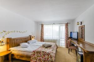 a bedroom with a bed and a desk and a television at Cheile Gradistei Fundata Resort in Fundata