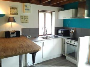 a kitchen with white cabinets and a sink and a table at Le Pti' chez vous in Saint-Omer