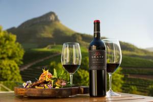 una bottiglia di vino e due bicchieri su un tavolo di Delaire Graff Lodges and Spa a Stellenbosch