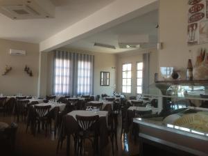 a dining room with tables and chairs and windows at Le Torri in Santa Marinella
