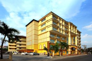 un edificio amarillo con coches estacionados frente a él en Victoria Nimman Hotel en Chiang Mai