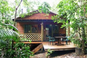 Cabaña de madera pequeña con mesa y sillas en Crater Lakes Rainforest Cottages, en Yungaburra