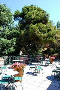 a patio with tables and chairs and a tree at Hotel Les Mazets Des Roches in Tarascon