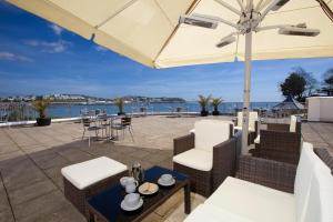 a patio with a table and chairs and an umbrella at Livermead Cliff Hotel in Torquay