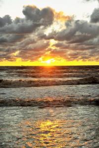 a sunset over the ocean with waves at Pakrantė in Klaipėda