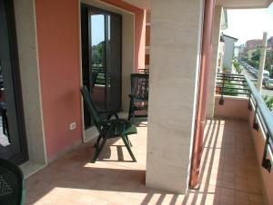 - un balcon avec une chaise verte dans un bâtiment dans l'établissement Residence Magnolia, à Grado