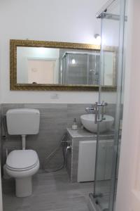 ein Badezimmer mit einem WC, einem Waschbecken und einem Spiegel in der Unterkunft Graziella House Holiday in Syrakus