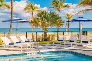 a pool with chairs and umbrellas and the beach at Plunge Beach Resort in Fort Lauderdale