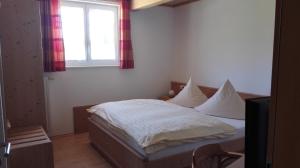 a bedroom with a bed with white sheets and a window at Pension Forsthaus Täle - das Gästehaus vom Schwarzwaldgasthaus Salenhof in Titisee-Neustadt