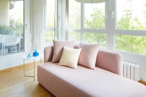 un sofá rosa en una sala de estar con ventanas en Playa de Ondarreta 2 by FeelFree Rentals, en San Sebastián
