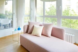 ein rosafarbenes Sofa im Wohnzimmer mit Fenstern in der Unterkunft Playa de Ondarreta 2 by FeelFree Rentals in San Sebastián