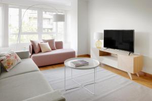 ein Wohnzimmer mit einer Couch, einem Fernseher und einem Tisch in der Unterkunft Playa de Ondarreta 2 by FeelFree Rentals in San Sebastián
